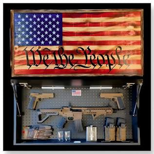 Display case with American flag and 'We The People' text, containing firearms and ammunition.